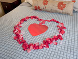 A romantic heart of petals on your king bed.