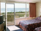 Balcony rooms with chairs overlook the end of the boardwalk and beach.