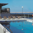 Outdoor pool surrounded by chairs with a nice view of the bay.