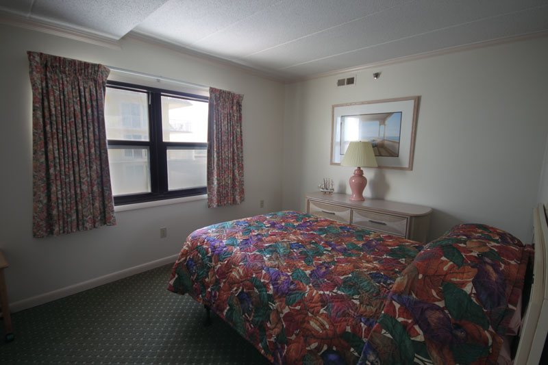 A bedroom with one queen bed and a window.